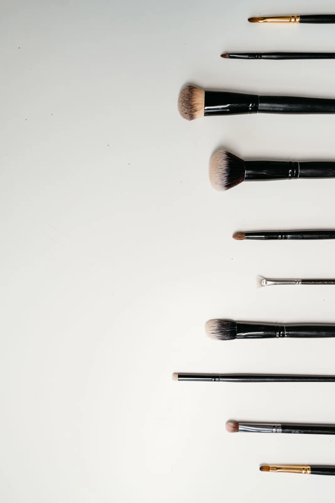 Makeup brushes laid along the edge of a light surface